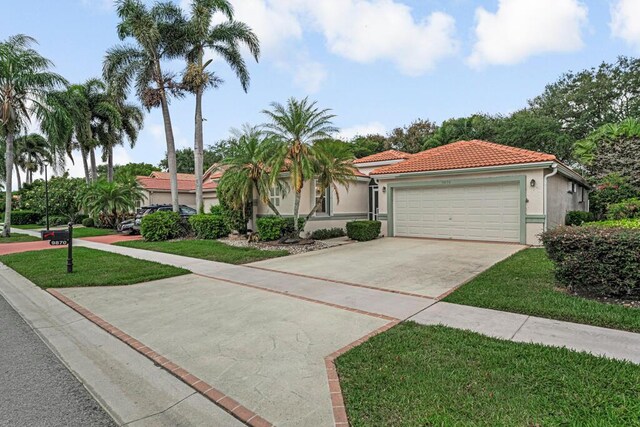9870 Harbour Lake Cir, Boynton Beach, FL 33437 - mediterranean / spanish-style home featuring a tiled roof, a front yard, concrete driveway, an attached garage, and stucco siding