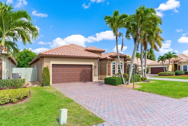 mediterranean / spanish-style home featuring an attached garage, stucco siding, a front yard, and a tile roof