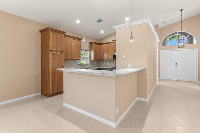 kitchen with brown cabinetry, light countertops, tasteful backsplash, a sink, and hanging light fixtures