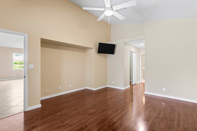 empty room featuring high vaulted ceiling, ceiling fan, baseboards, and wood finished floors