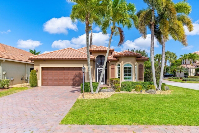 mediterranean / spanish-style home with an attached garage, driveway, a front yard, and stucco siding