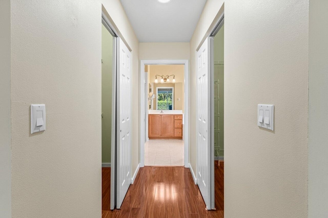 corridor featuring dark wood-style flooring, a textured wall, and baseboards