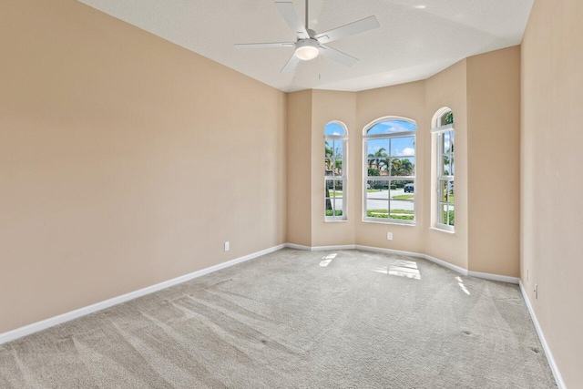 carpeted empty room with baseboards and a ceiling fan