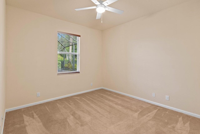 empty room with a ceiling fan, baseboards, and light colored carpet