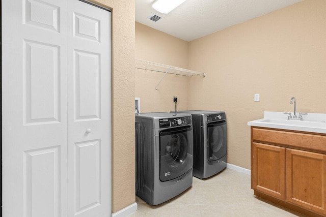 laundry area featuring light tile patterned flooring, a sink, baseboards, visible vents, and washing machine and dryer