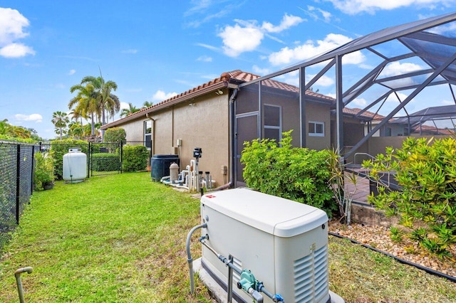 exterior space featuring a tile roof, stucco siding, a fenced backyard, a lanai, and a yard