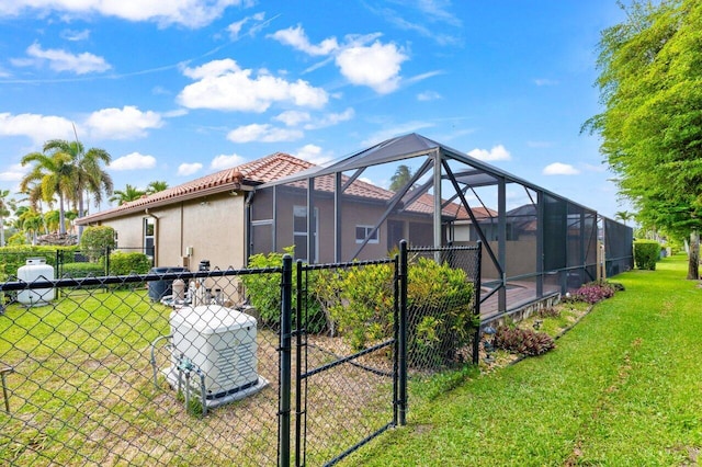 back of property featuring a tile roof, a lawn, a gate, fence, and stucco siding