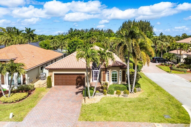 view of front of property featuring a tiled roof, a garage, decorative driveway, a front lawn, and stucco siding