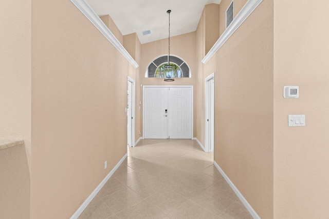 interior space with light tile patterned floors, a high ceiling, visible vents, and baseboards