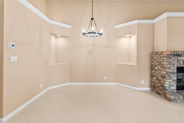 unfurnished dining area featuring a brick fireplace, baseboards, an inviting chandelier, and tile patterned flooring