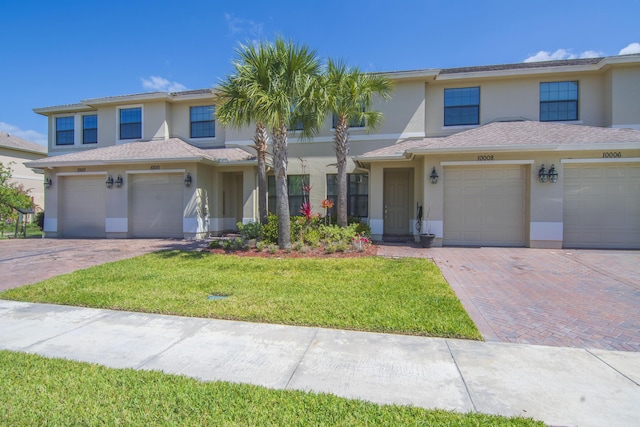 traditional-style home with a garage, stucco siding, driveway, and a front lawn