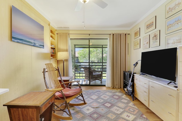 sitting room featuring light wood-style floors, a ceiling fan, and ornamental molding