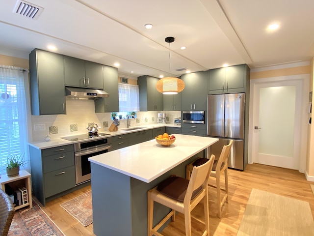 kitchen with decorative backsplash, visible vents, a sink, under cabinet range hood, and stainless steel appliances