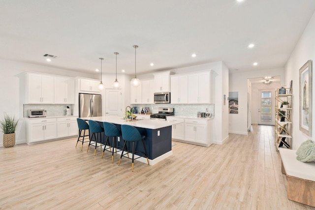 14175 SW Harker St, Port Saint Lucie, FL 34987 - kitchen with appliances with stainless steel finishes, a sink, backsplash, light countertops, and a kitchen bar
