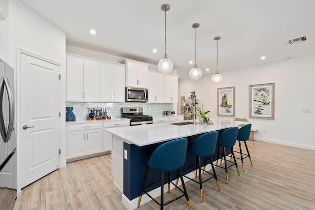 14175 SW Harker St, Port Saint Lucie, FL 34987 - kitchen featuring appliances with stainless steel finishes, a sink, decorative backsplash, light wood-style flooring, and recessed lighting
