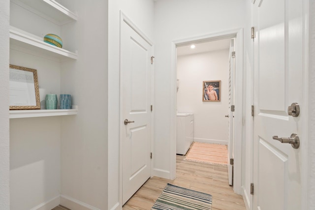 14175 SW Harker St, Port Saint Lucie, FL 34987 - hallway with separate washer and dryer, light wood finished floors, and baseboards