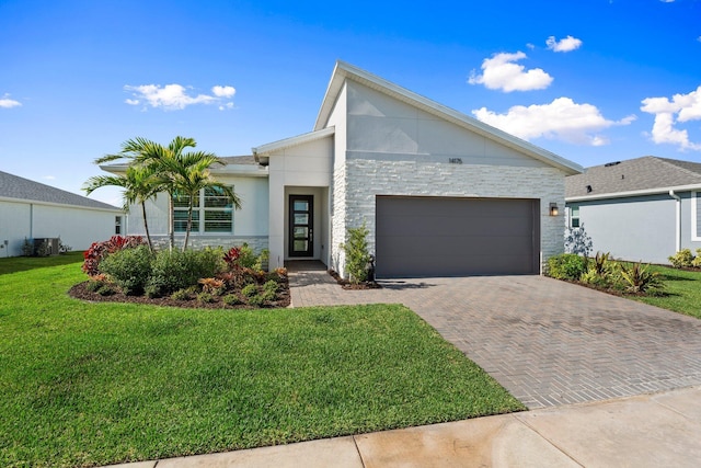 14175 SW Harker St, Port Saint Lucie, FL 34987 - view of front of home featuring an attached garage, decorative driveway, a front yard, and stone siding