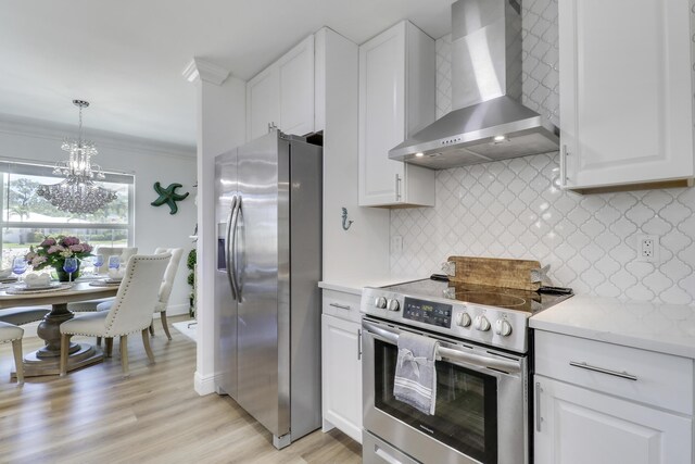 18315 SE Courtview Cir, Tequesta, FL 33469 - kitchen featuring white cabinets, crown molding, a notable chandelier, wall chimney exhaust hood, and stainless steel appliances