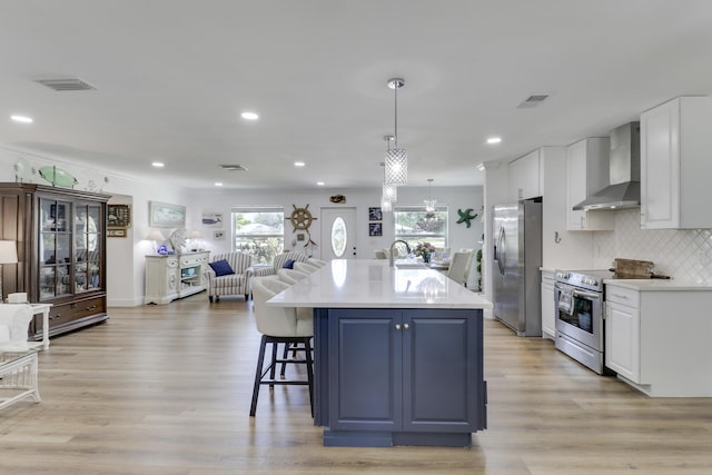 18315 SE Courtview Cir, Tequesta, FL 33469 - kitchen featuring wall chimney range hood, white cabinets, stainless steel appliances, open floor plan, and visible vents