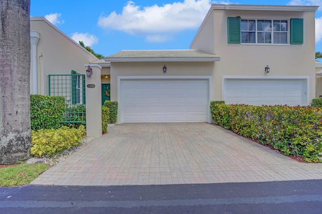 townhome / multi-family property with an attached garage, decorative driveway, and stucco siding