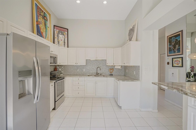 kitchen with light stone countertops, a sink, stainless steel appliances, decorative backsplash, and light tile patterned floors
