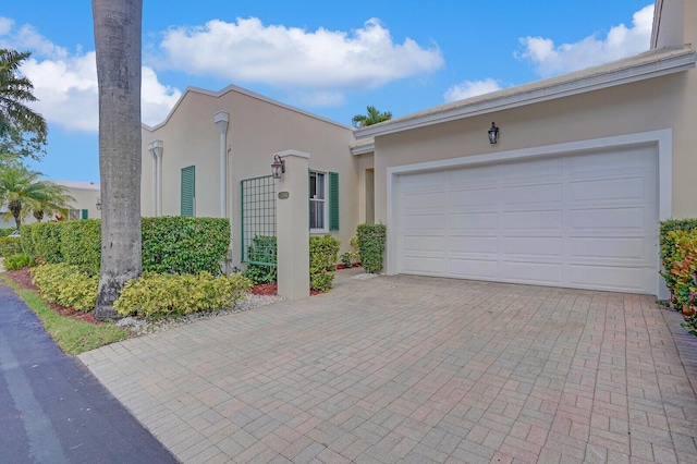 view of front facade with decorative driveway, a garage, and stucco siding