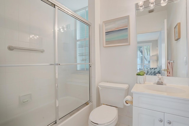 full bathroom with vanity, bath / shower combo with glass door, toilet, and visible vents