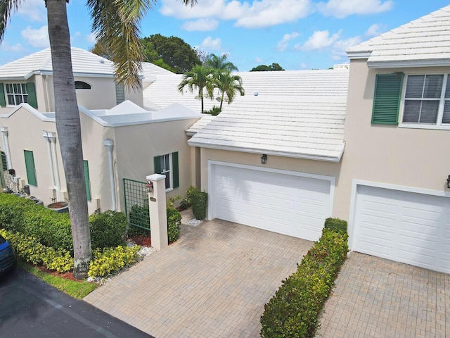 view of property with decorative driveway, a tile roof, and stucco siding