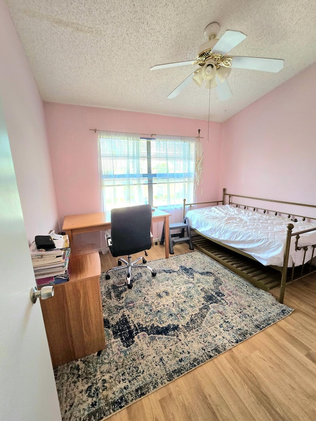 bedroom featuring a textured ceiling, ceiling fan, and wood finished floors