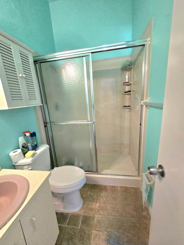 bathroom featuring vanity, a shower stall, and toilet