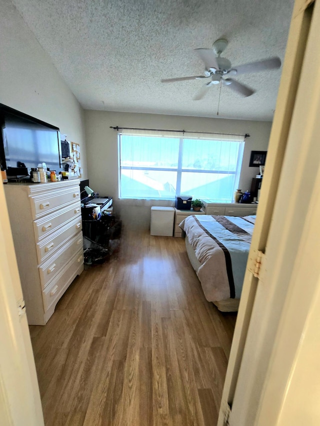 bedroom featuring a textured ceiling, ceiling fan, and wood finished floors
