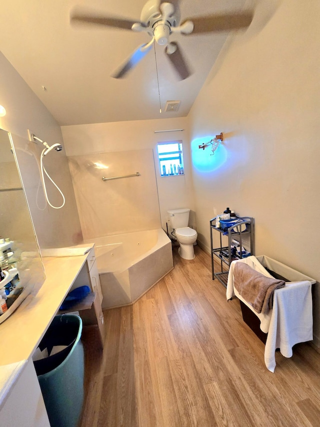full bathroom featuring ceiling fan, toilet, wood finished floors, vaulted ceiling, and visible vents