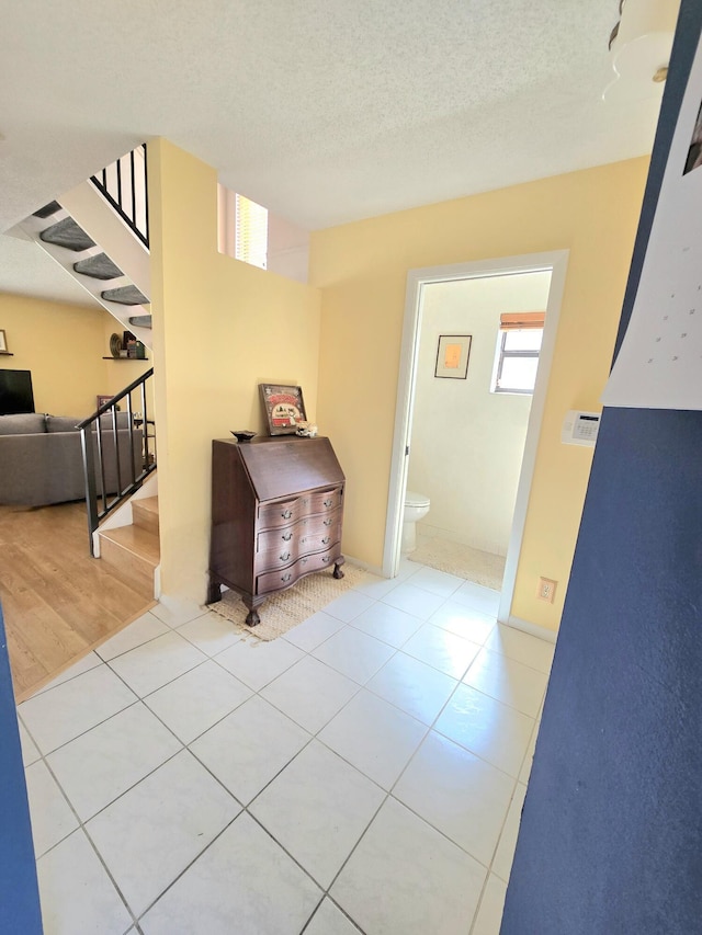 hall featuring stairs, a textured ceiling, and tile patterned flooring