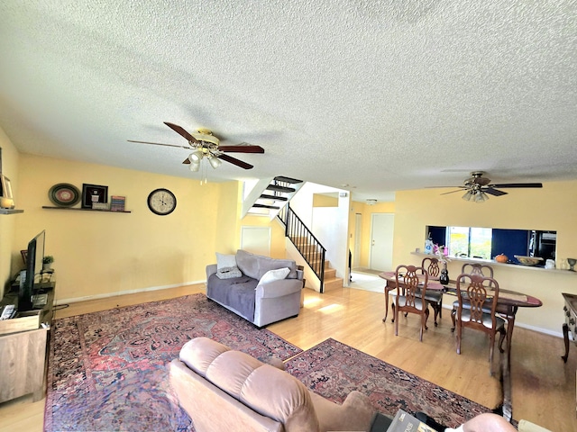 living room featuring a textured ceiling, ceiling fan, and stairway