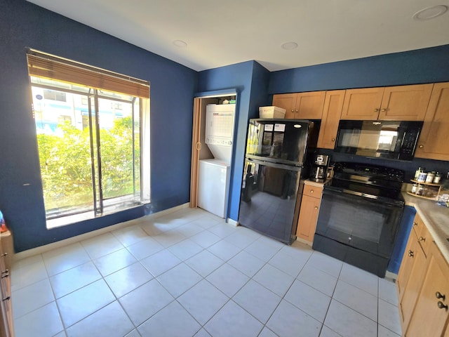 kitchen featuring light countertops, light tile patterned floors, stacked washer / dryer, and black appliances