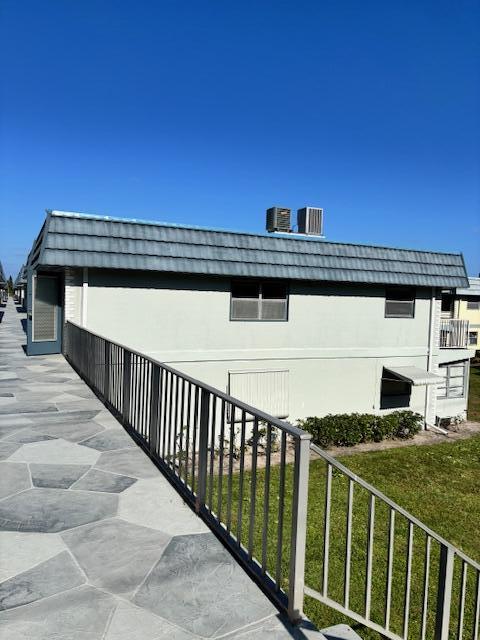 view of property exterior featuring a yard, stucco siding, and mansard roof