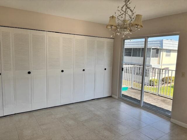 unfurnished bedroom with access to outside, baseboards, a notable chandelier, and multiple windows