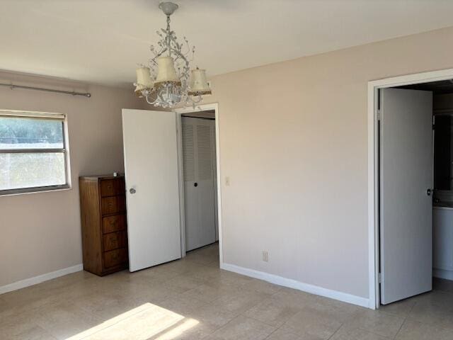unfurnished bedroom featuring baseboards and a chandelier