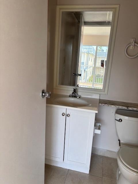 half bath with vanity, tile patterned floors, and toilet