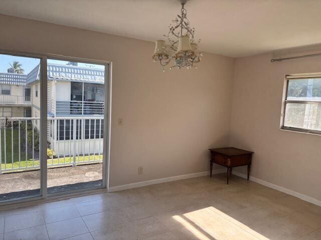 tiled spare room with an inviting chandelier and baseboards