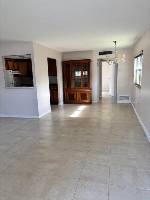 spare room featuring baseboards, a chandelier, and visible vents