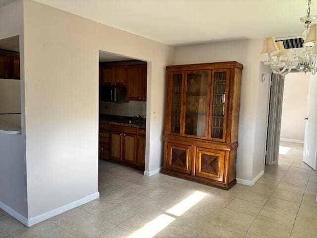 unfurnished dining area featuring light tile patterned flooring, baseboards, an inviting chandelier, and visible vents
