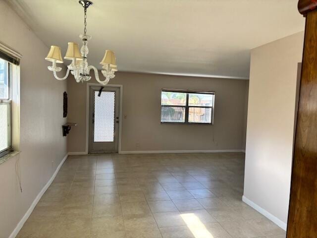 unfurnished room featuring an inviting chandelier, baseboards, and light tile patterned flooring
