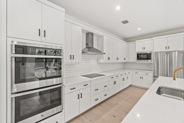 9610 Sterling Shores St, Delray Beach, FL 33446 - kitchen featuring wall chimney exhaust hood, stainless steel appliances, a sink, light countertops, and white cabinets