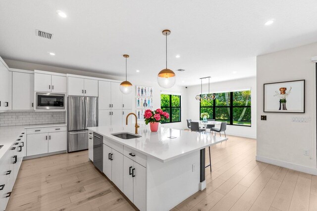 9610 Sterling Shores St, Delray Beach, FL 33446 - kitchen featuring a sink, stainless steel appliances, light wood-style floors, recessed lighting, and white cabinets