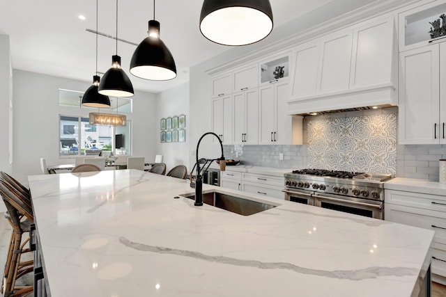 kitchen with a sink, decorative backsplash, double oven range, and white cabinetry