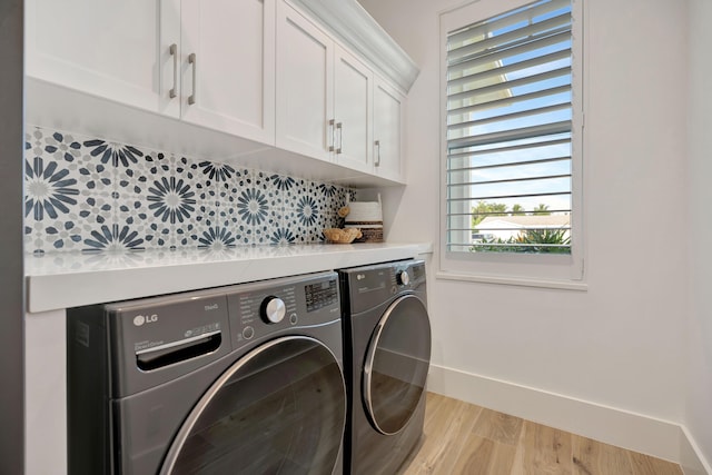 laundry room featuring washer and clothes dryer, cabinet space, light wood finished floors, and a wealth of natural light