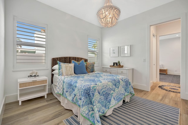 bedroom with baseboards, light wood finished floors, and a chandelier
