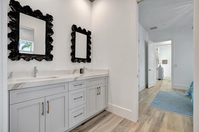 bathroom featuring double vanity, a sink, and wood finished floors