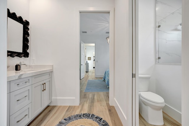 bathroom featuring walk in shower, vanity, toilet, baseboards, and wood finished floors